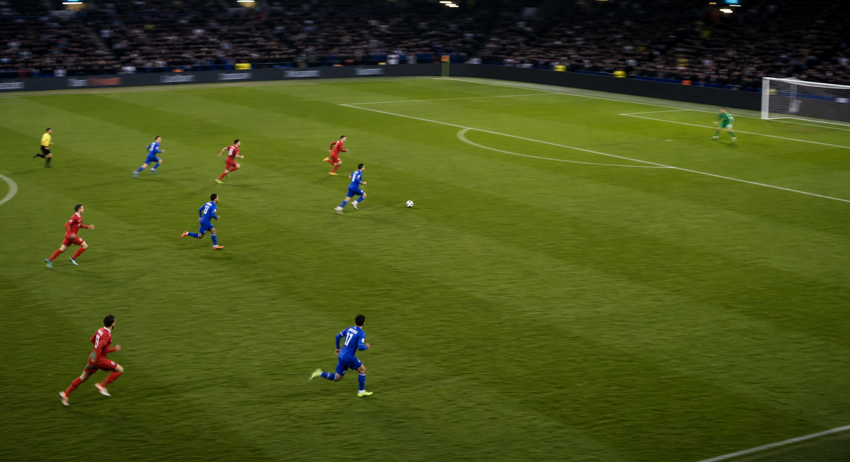 야간 축구장에서 역습 상황처럼 선수들이 열린 공간으로 달리는 장면